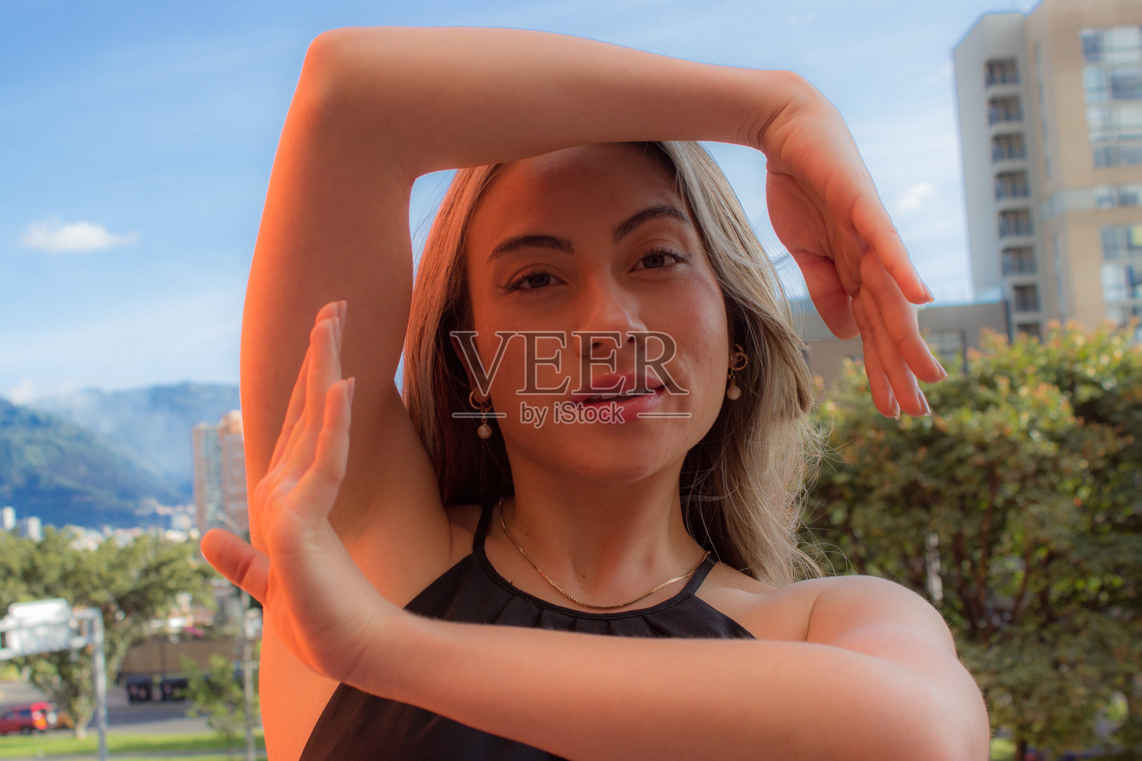 美丽的年轻女子穿着黑色连衣裙，以城市为背景摆姿势照片摄影图片