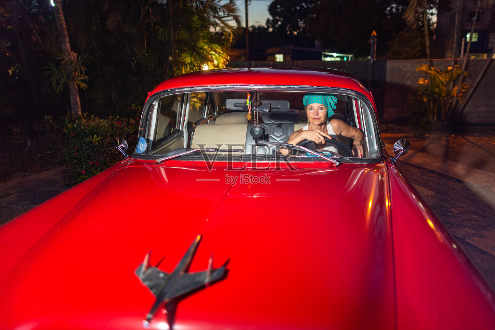 在古巴哈瓦那，一位妇女开着一辆红色的老式美国车照片摄影图片