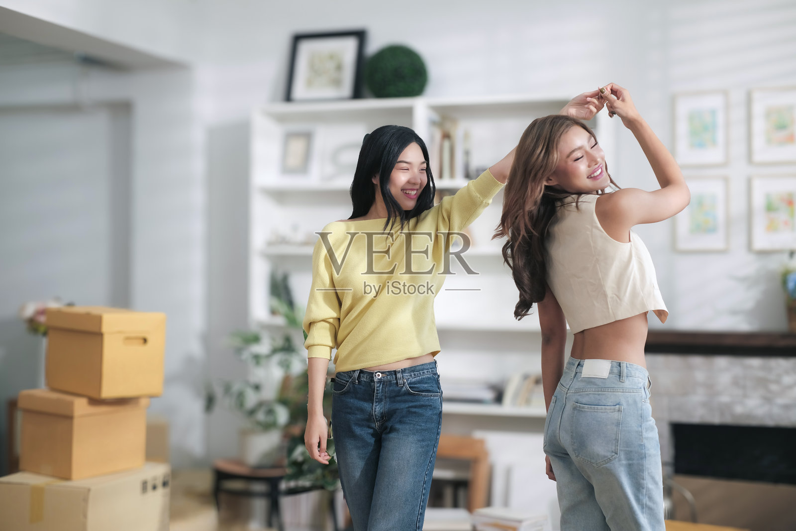 两位可爱的亚洲女性在家中快乐地跳舞，因为她们对自己成功的在线业务感到高兴。照片摄影图片