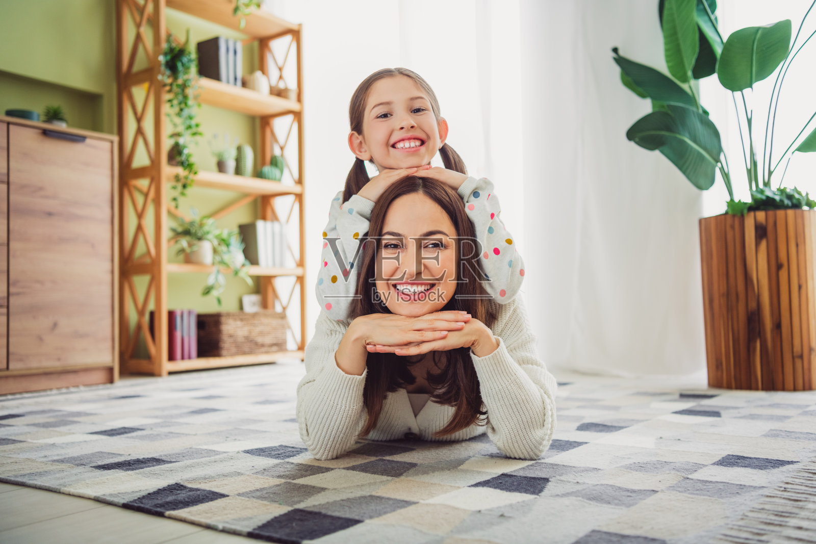 快乐的年轻母亲和女儿在明亮的客厅中享受愉快的亲子时光照片摄影图片