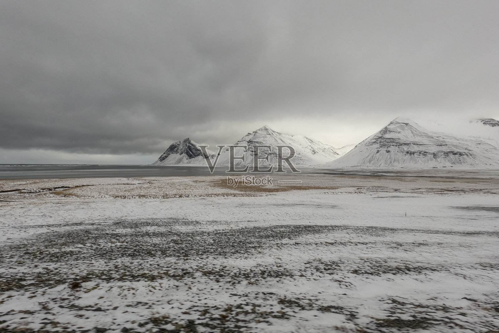 冰岛南部斯托克斯内斯海滩附近的维斯特拉霍恩山脉，白雪覆盖的山脉在多云的天空下。照片摄影图片
