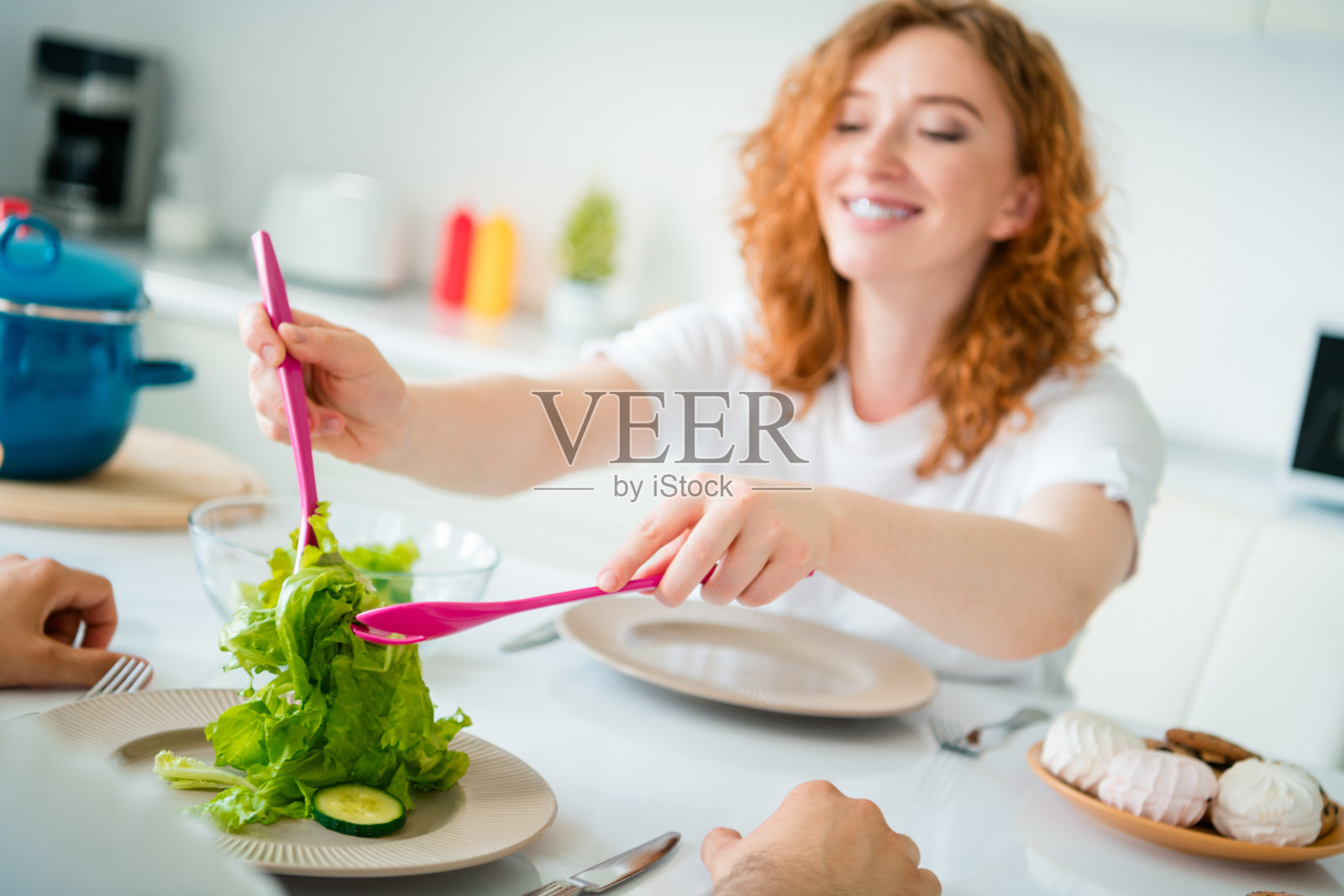 迷人的红发女性在明亮的厨房里愉快地准备新鲜沙拉照片摄影图片