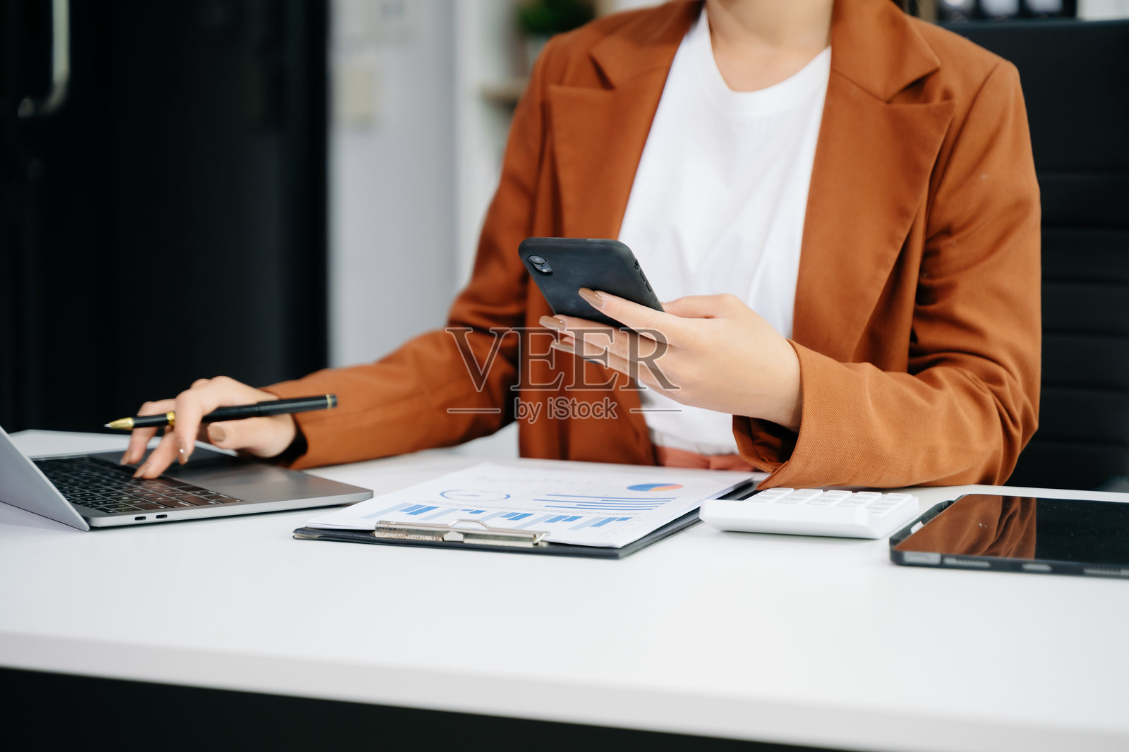女商人在使用智能手机和平板电脑的同时，手握现代新型电脑，体现了现代工作的概念。照片摄影图片