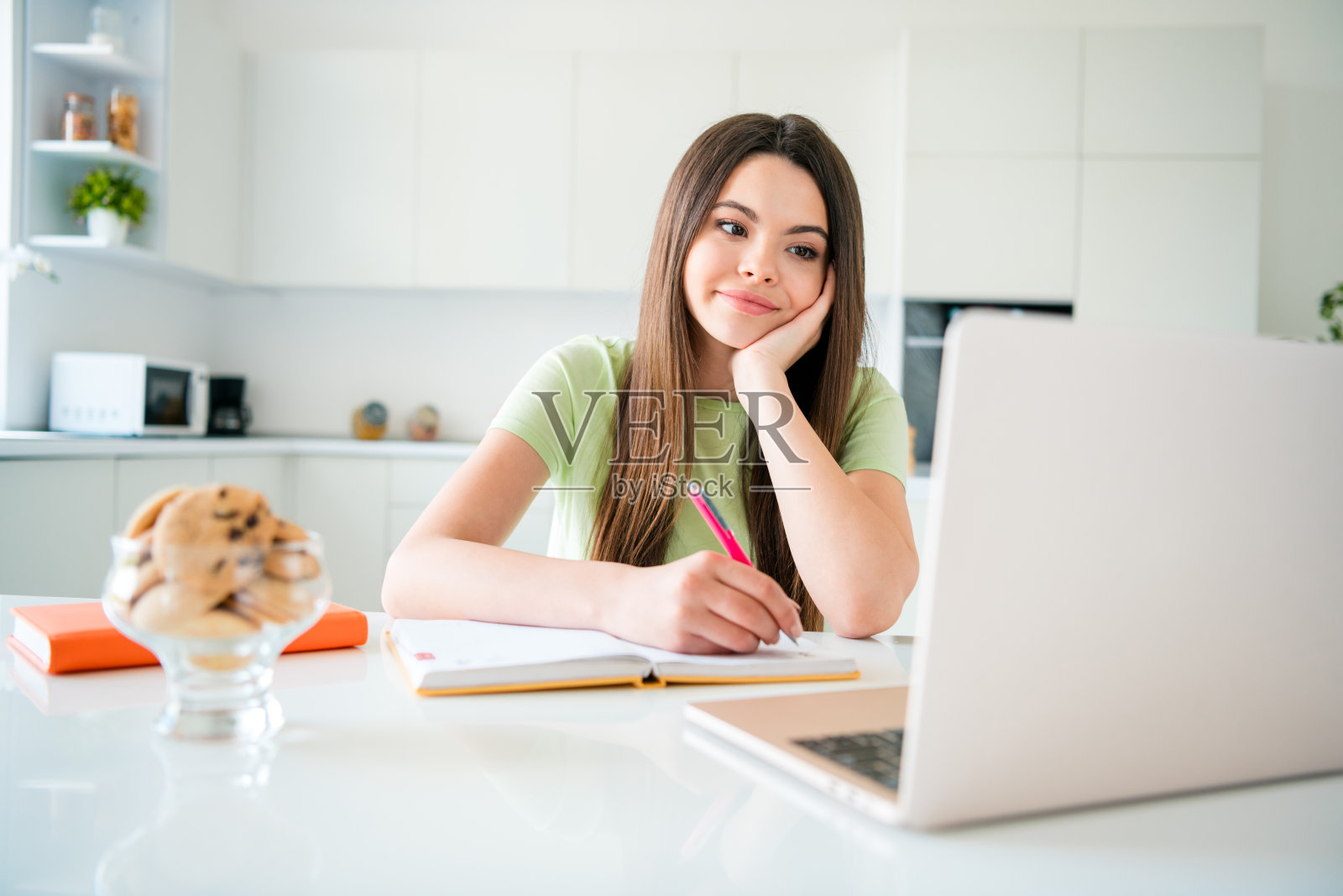 年轻女孩在明亮的厨房环境中享受学习时光，写笔记。照片摄影图片