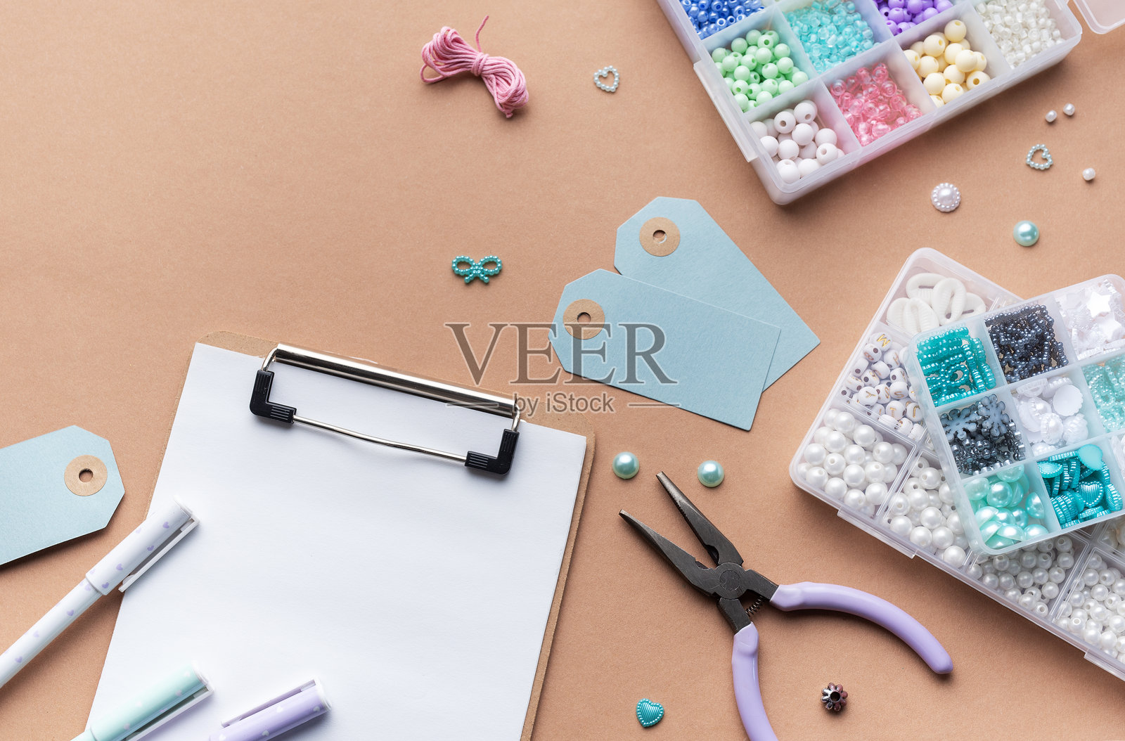 手工艺用品在工作台上整齐摆放，包括珠子、工具和个性化珠宝制作标签照片摄影图片