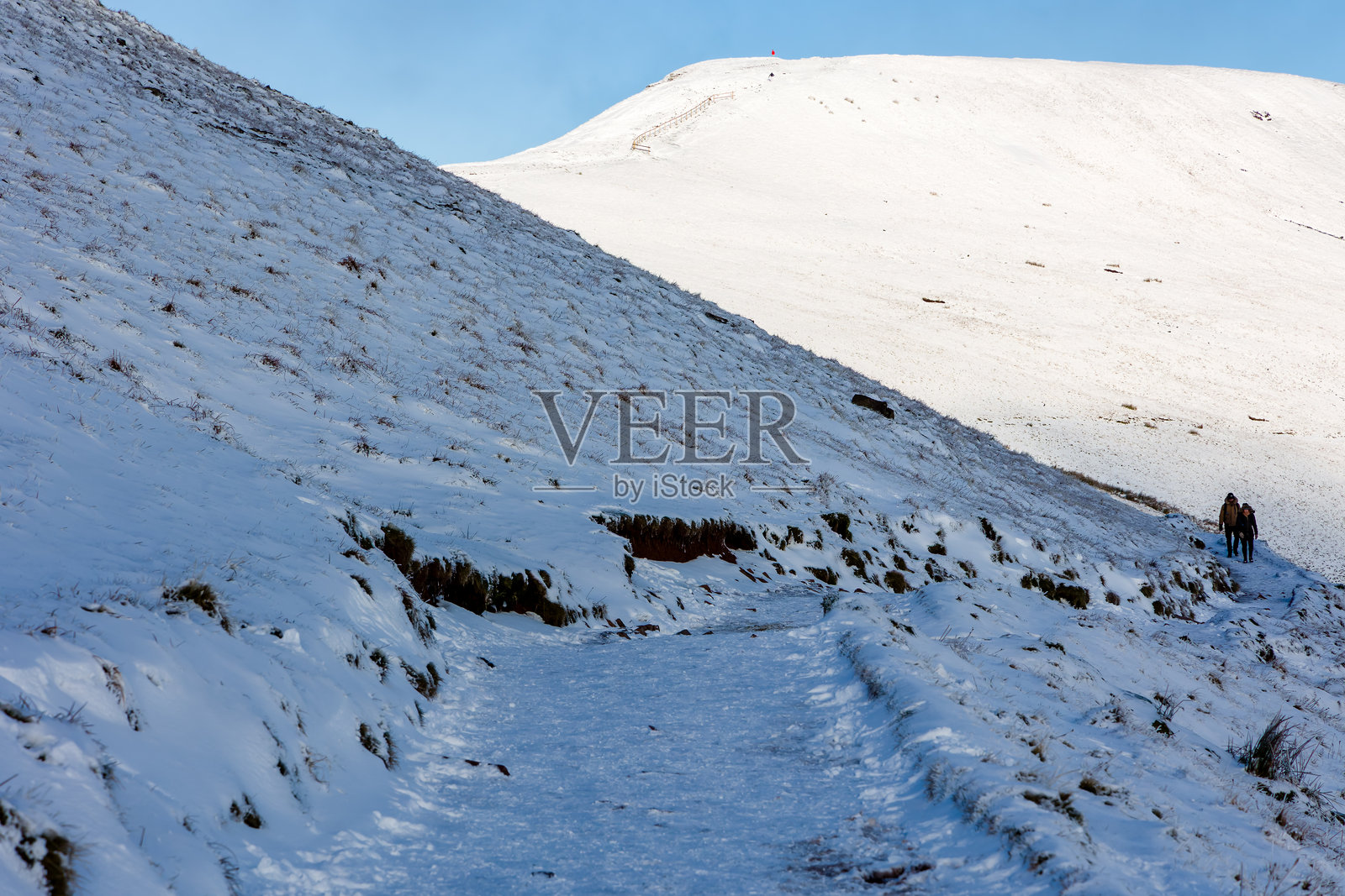 在寒冷多雪的冬季，登山者正在布雷肯比肯斯的佩尼凡山下山。照片摄影图片