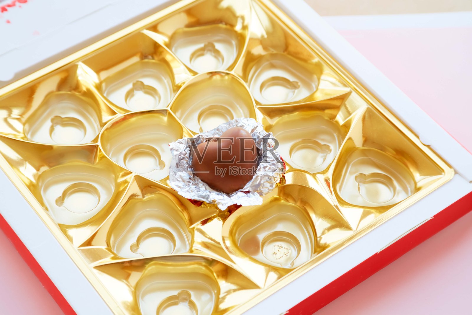 一个装有单颗心形巧克力糖果的糖果盒，包装打开，情人节糖果，盒子里的心形巧克力，爱的告白，敞开的心。照片摄影图片