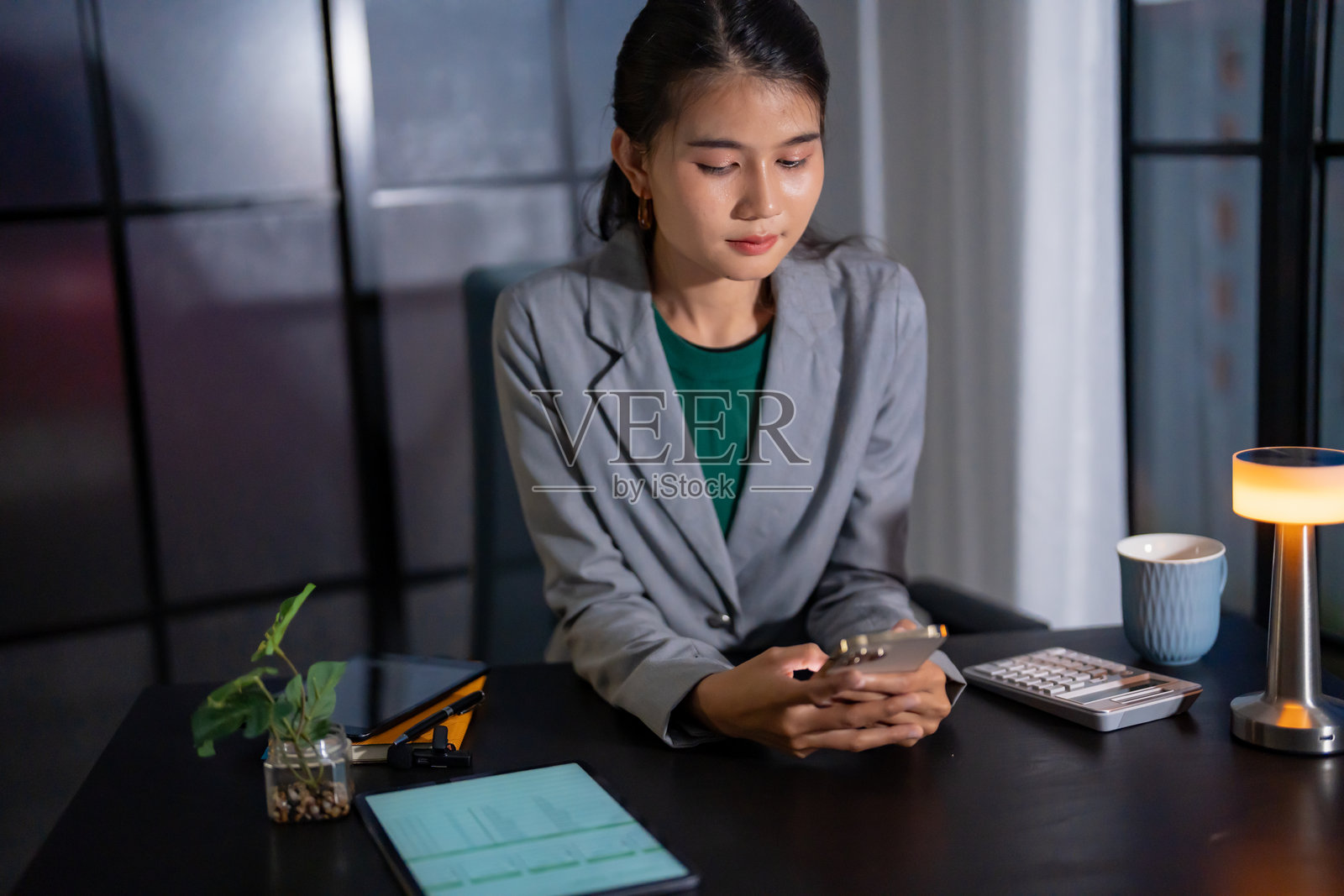 深夜独自工作。亚洲女商人在黑暗的办公室里，晚上在桌子上使用笔记本电脑工作。照片摄影图片