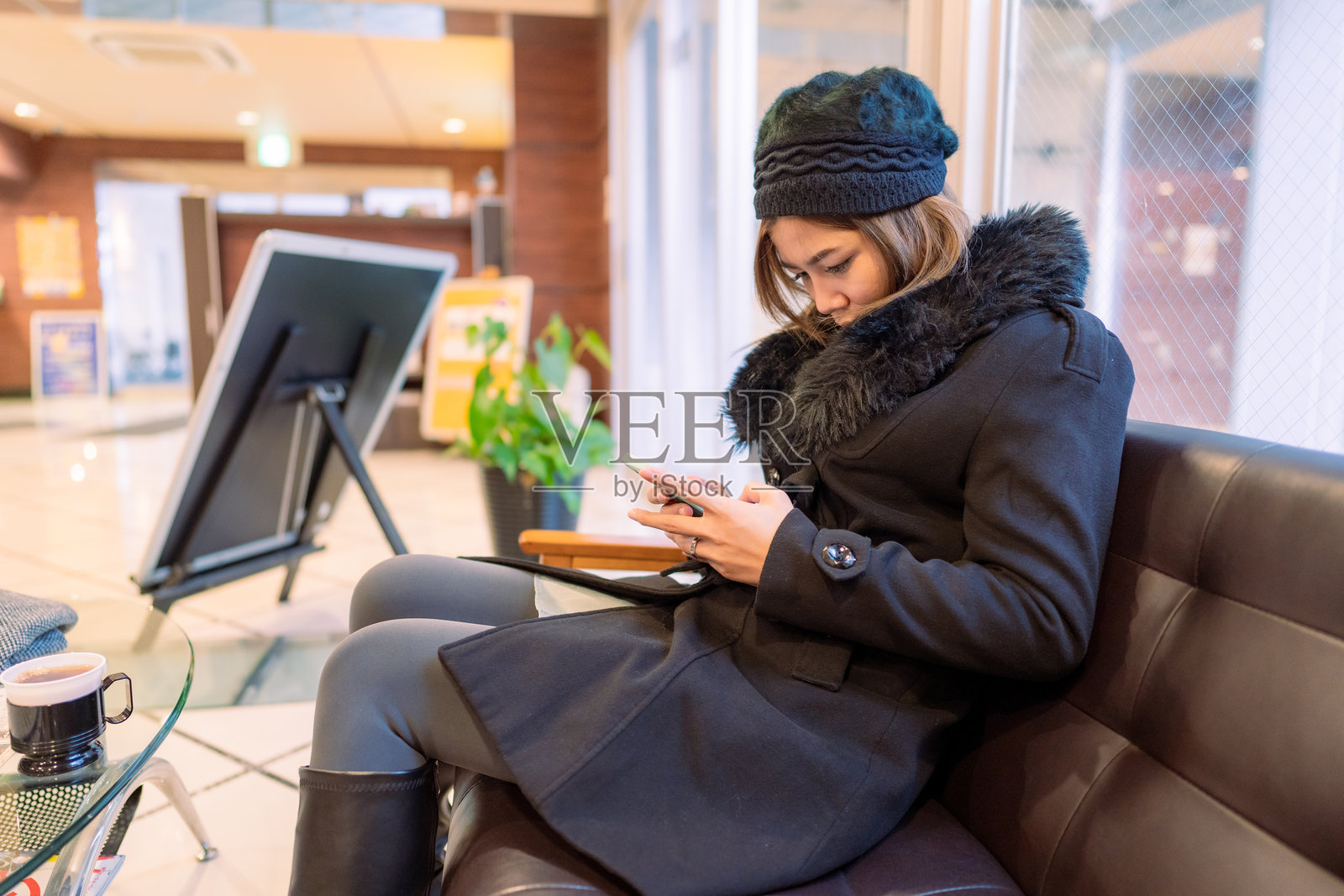一位女士坐在酒店大堂使用智能手机照片摄影图片