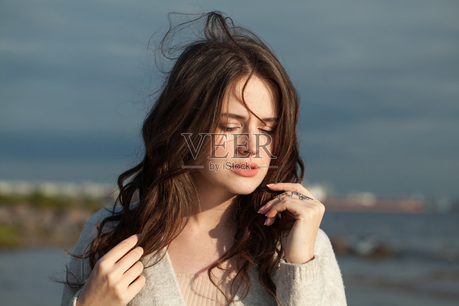 一个春天的早晨，优雅的年轻女模特，棕色头发，自然妆容，沿着度假胜地的海岸散步。幸福、平衡、宁静、情感和心情的概念。闭上眼睛照片摄影图片