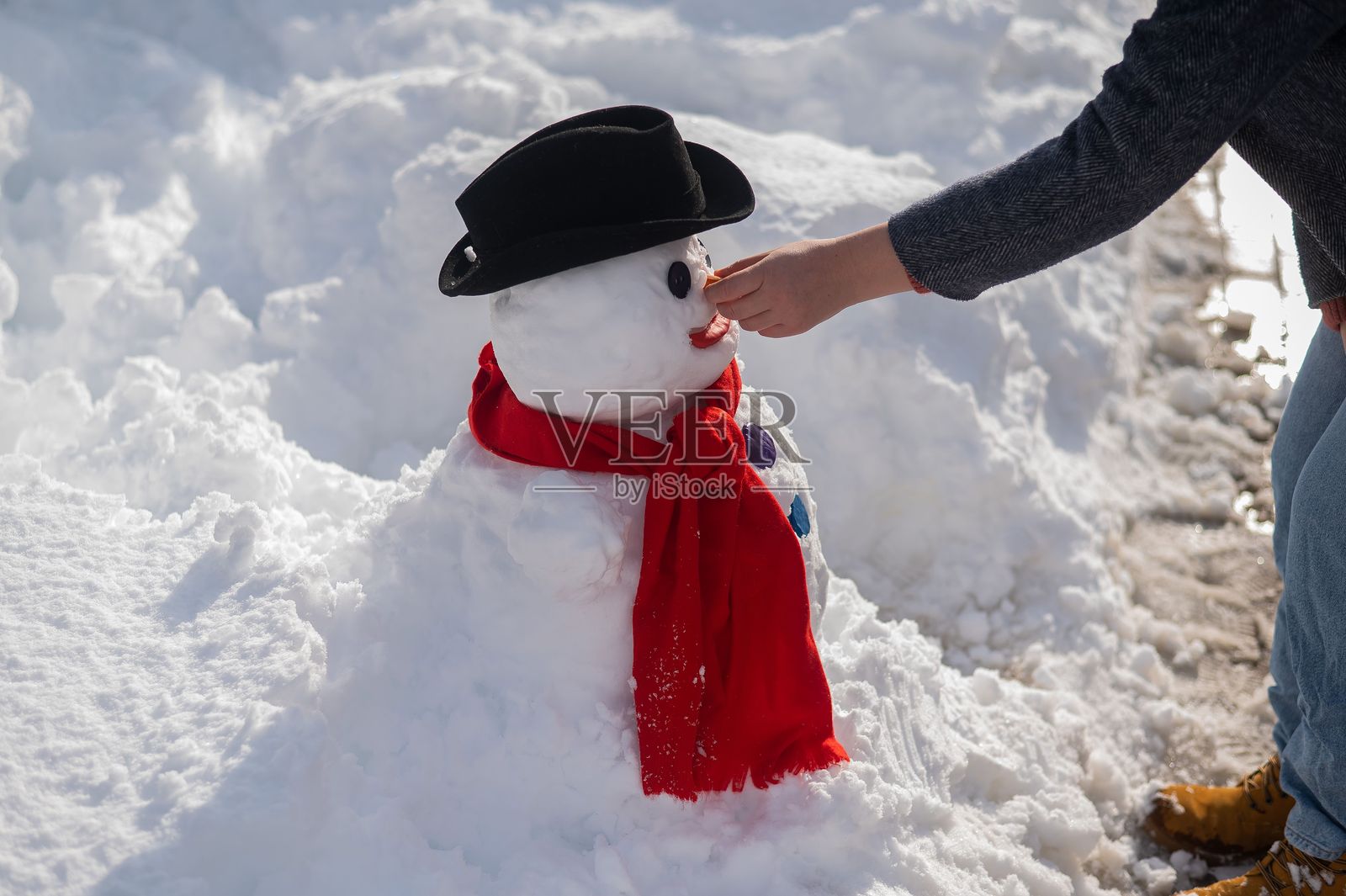 一个白人妇女用雪雕刻雪人。胡萝卜是鼻子的位置。照片摄影图片