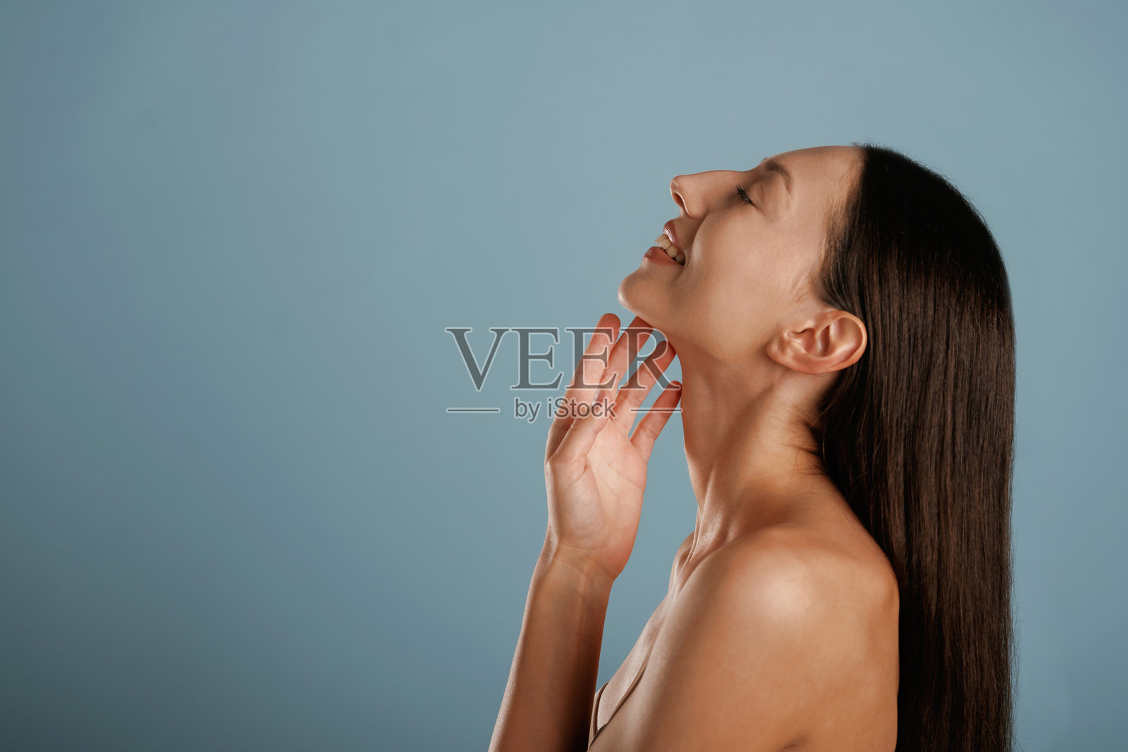 光滑洁净的肌肤，摆姿势。年轻女性在工作室背景前。照片摄影图片