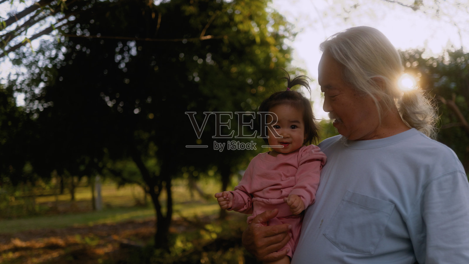 快乐的老人抱着心爱的孙子在农场。照片摄影图片