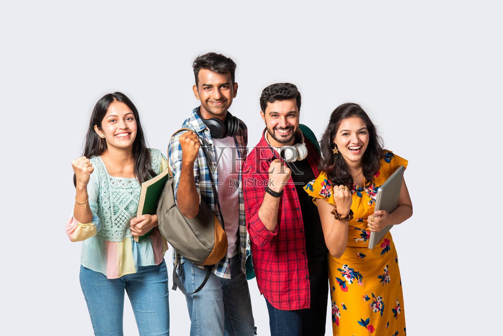四个年轻的印度亚裔大学朋友带着背包，书，笔记本电脑，站在孤立的白色，在图书馆学习照片摄影图片