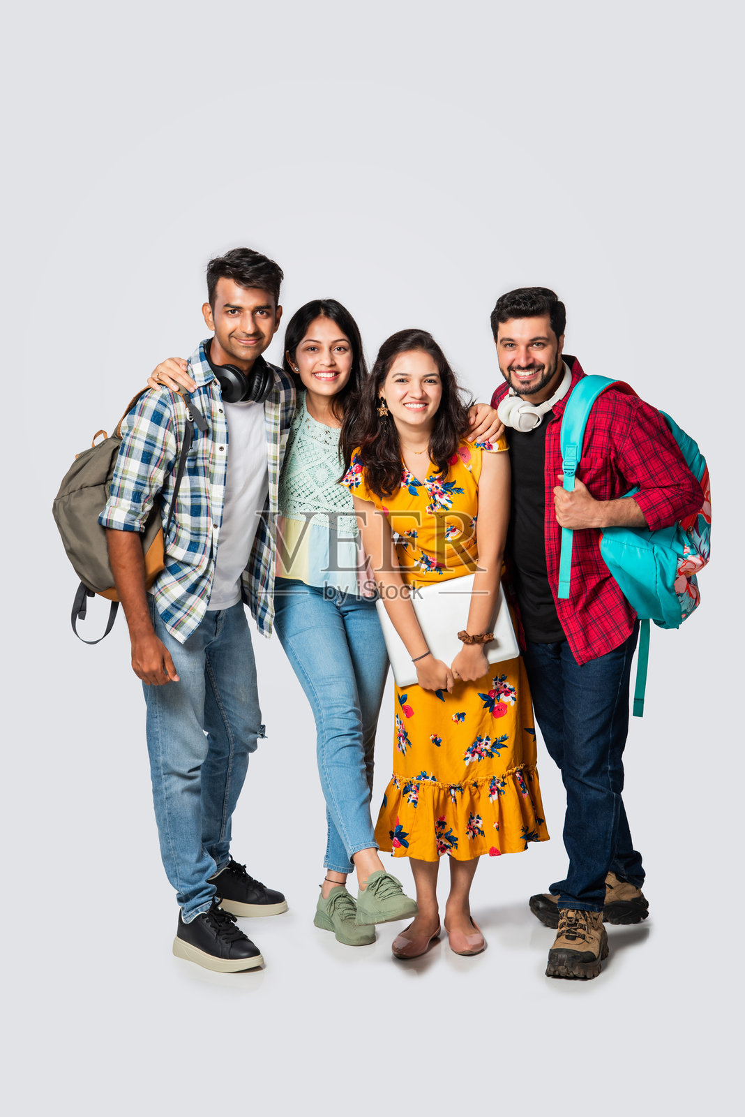 四个年轻的印度亚裔大学朋友带着背包，书，笔记本电脑，站在孤立的白色，在图书馆学习照片摄影图片