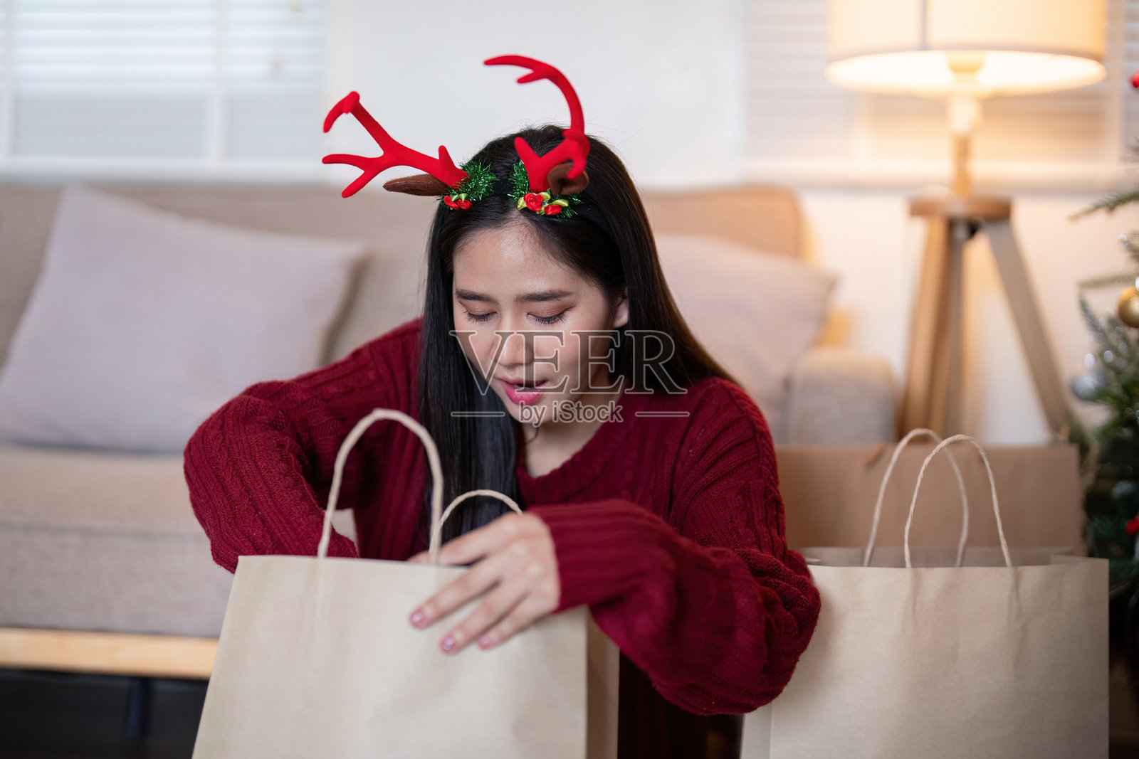 戴着驯鹿角的亚洲女性在探索礼品袋照片摄影图片