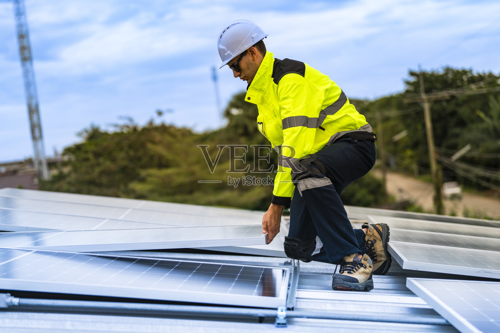 技术人员在安装过程中抬起光伏面板，展示可再生能源的进步。穿着安全装备，体现对绿色能源解决方案和可持续发展的关注。照片摄影图片