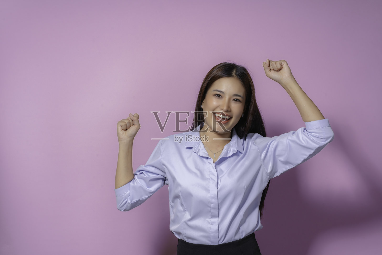 年轻的女商人在空中举起拳头，开心地微笑着，庆祝最近生意上的成功或成就照片摄影图片