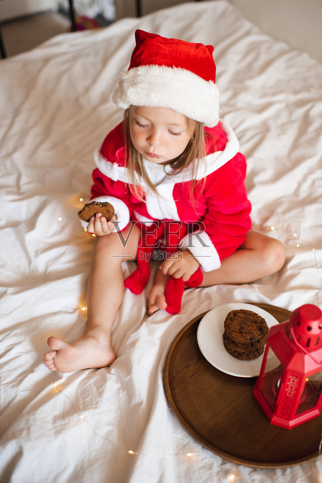 可爱的女婴戴着圣诞老人的帽子躺在床上照片摄影图片