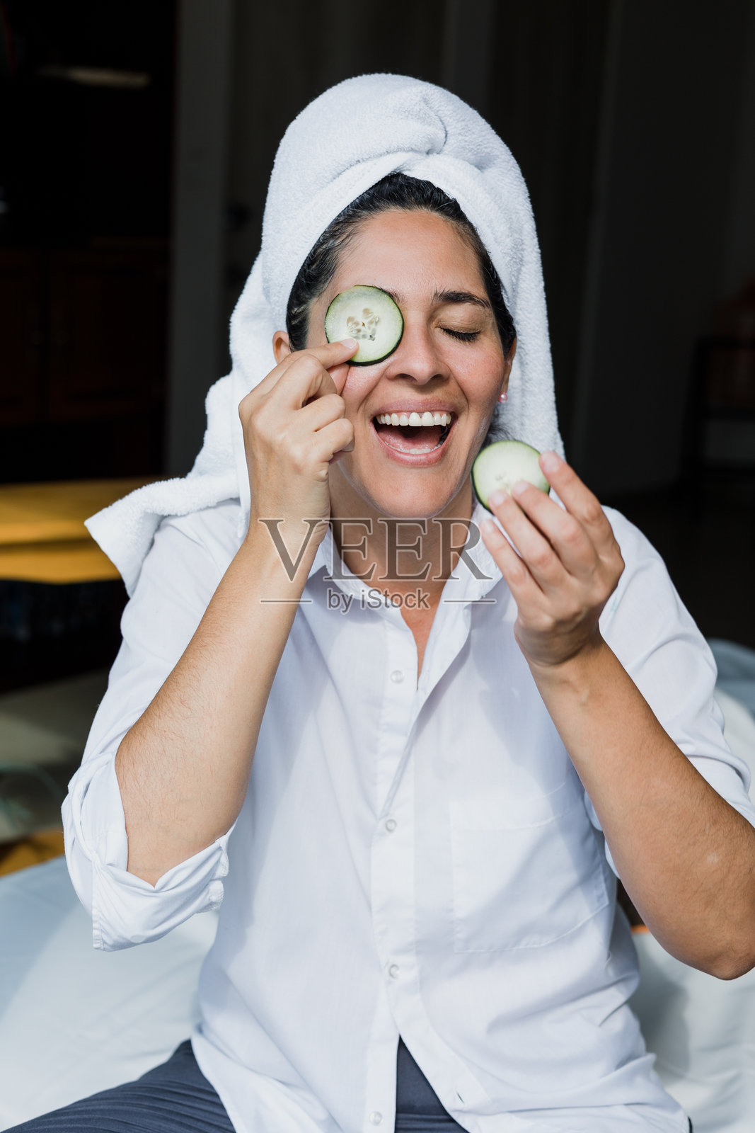 拉丁裔成年女性在墨西哥的家中使用黄瓜片敷面膜进行去角质护理，属于西班牙裔人群。照片摄影图片