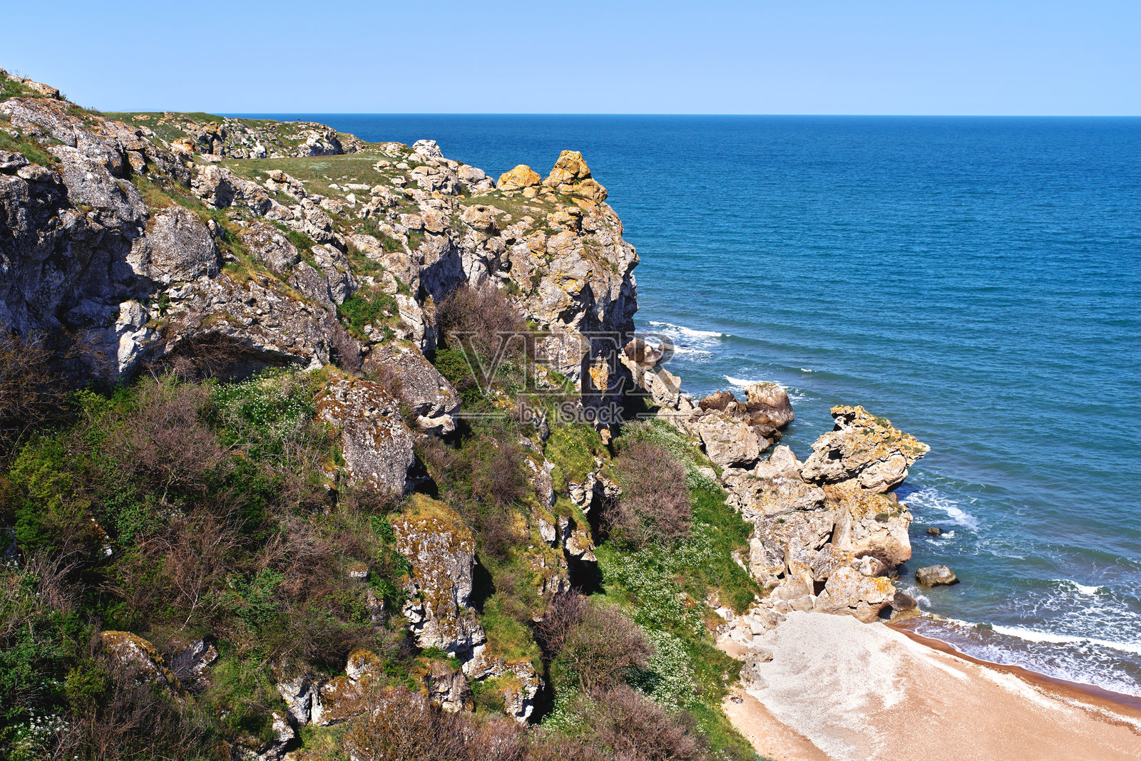 蓝色海洋、岩石海滩和绿草覆盖的海岸照片摄影图片