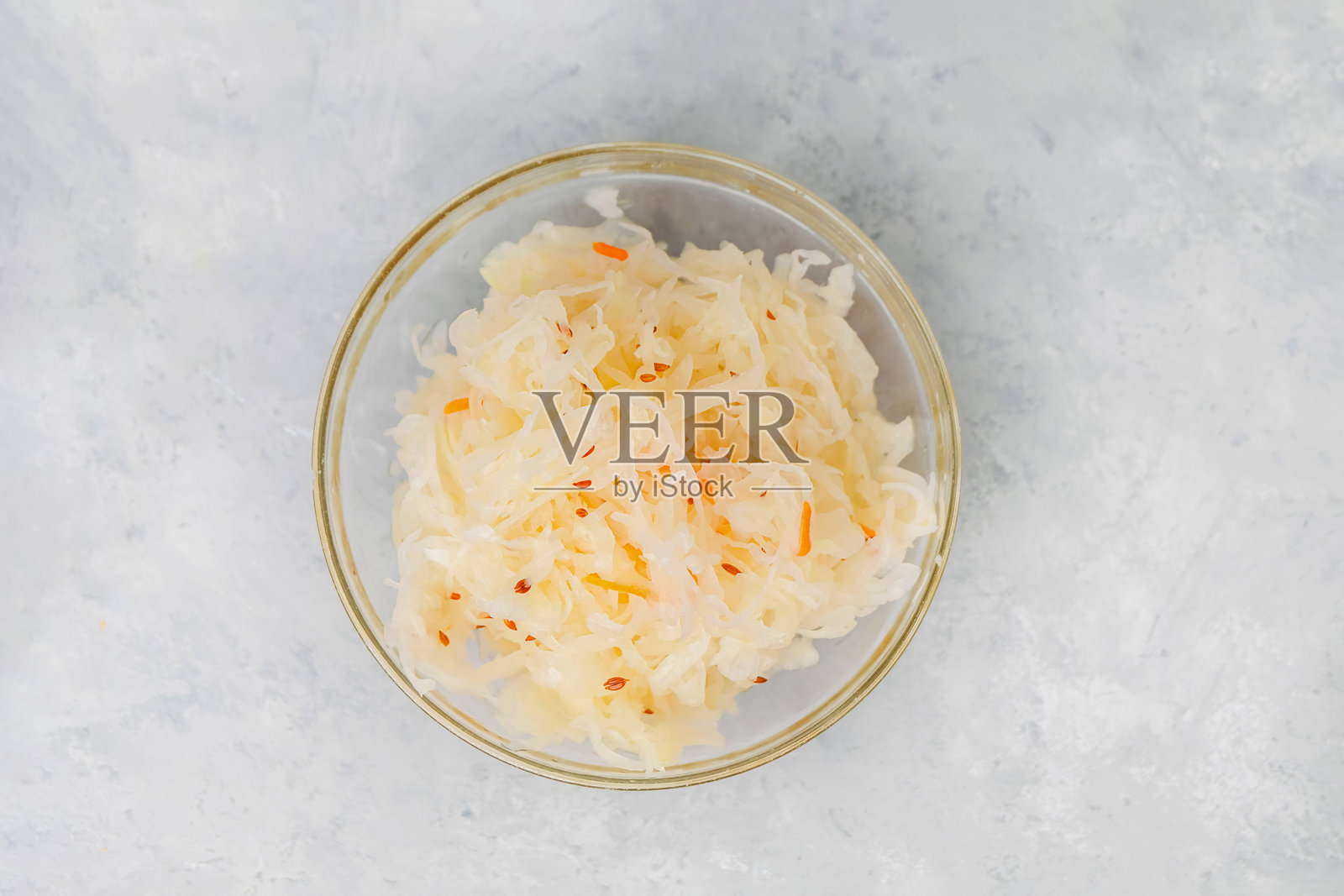 从上方看装有酸菜的盘子，背景为中性色调。发酵食品概念照片摄影图片