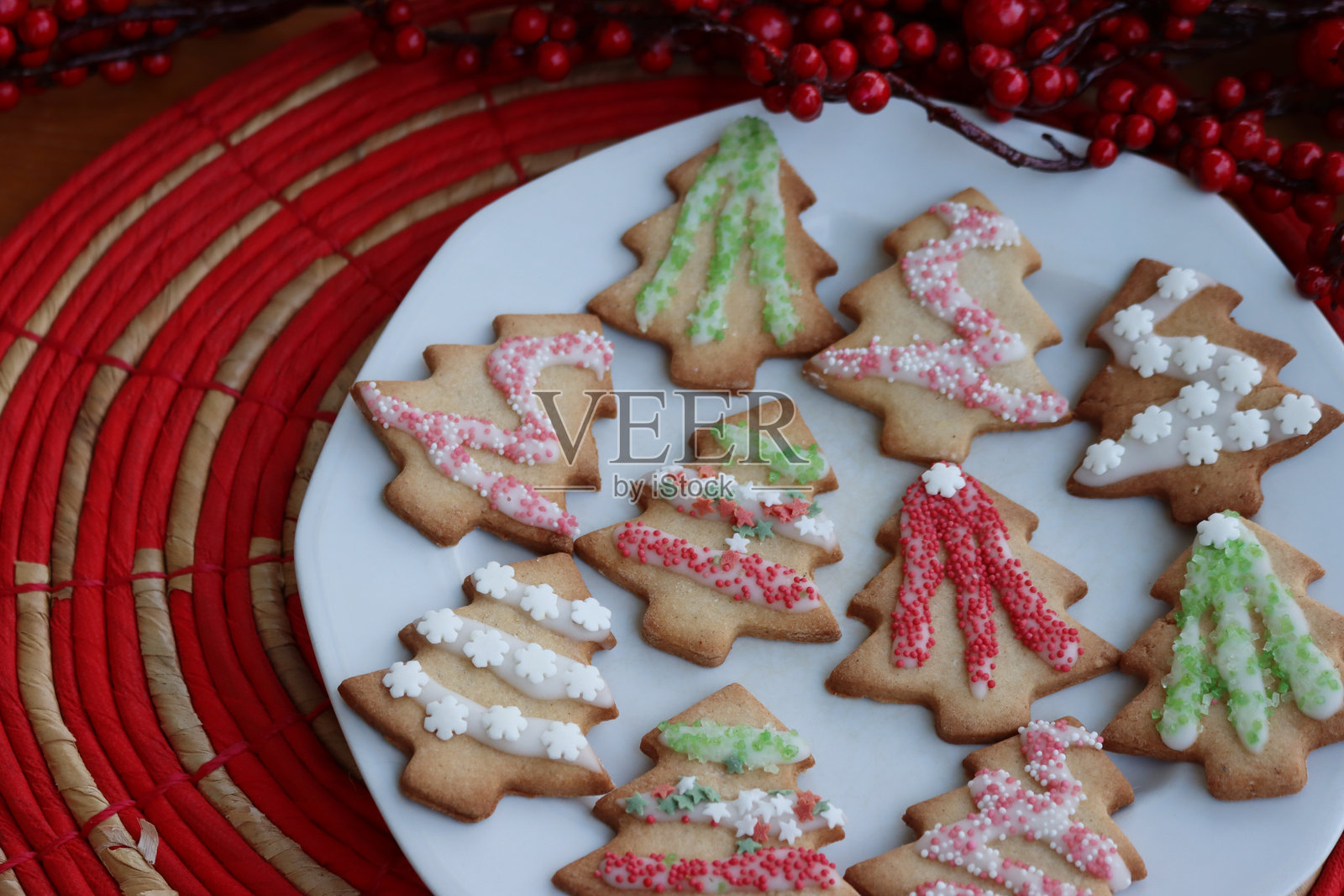 圣诞树形状的姜饼饼干放在盘子上，桌子上有装饰品照片摄影图片