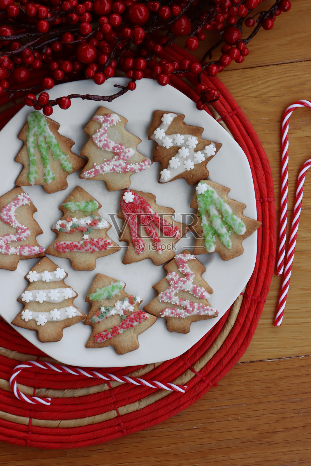 圣诞树形状的姜饼饼干放在盘子上，桌子上有装饰品照片摄影图片
