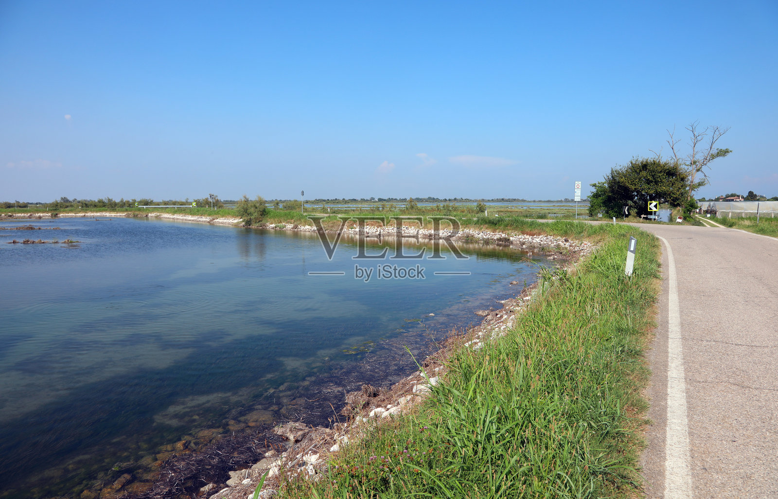 一条狭窄的道路穿过位于意大利北部威尼斯附近的泻湖，底部泥泞且水浅。照片摄影图片