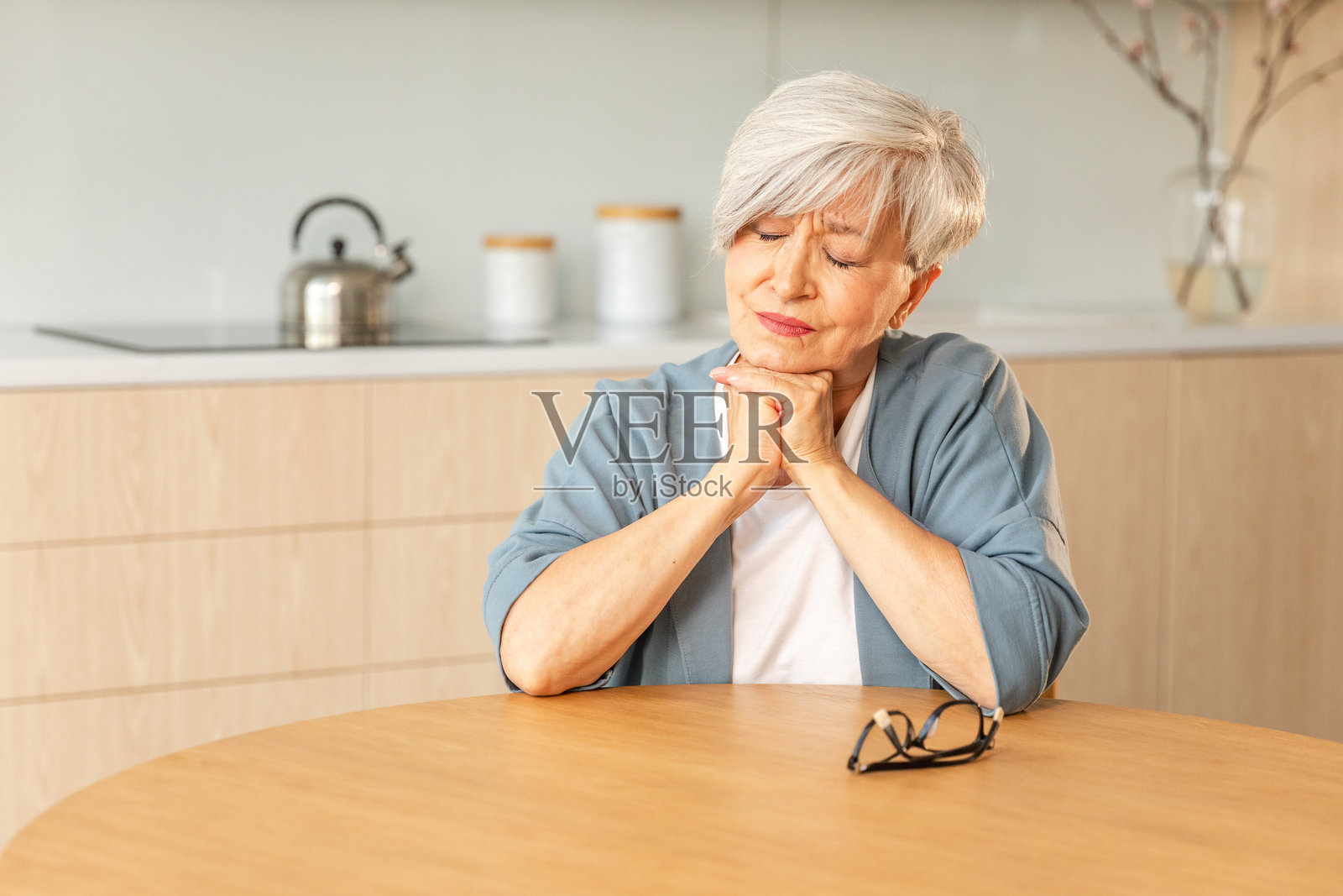 悲伤疲惫的生病孤独失望的老年女性独自坐在家中。感到不快乐的成熟祖母正在经历亲人去世的悲痛和坏消息。感到压力的老年女性正在忍受孤独。照片摄影图片