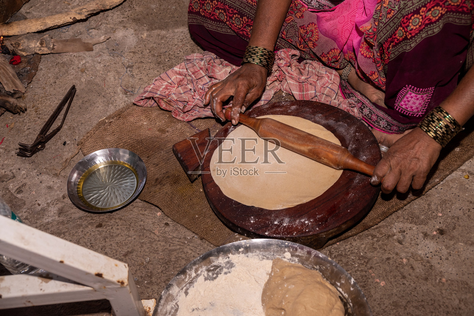 一位村庄妇女在炉子上做面包。用泥炉烤制面包，制作罗蒂，在乡村中。照片摄影图片