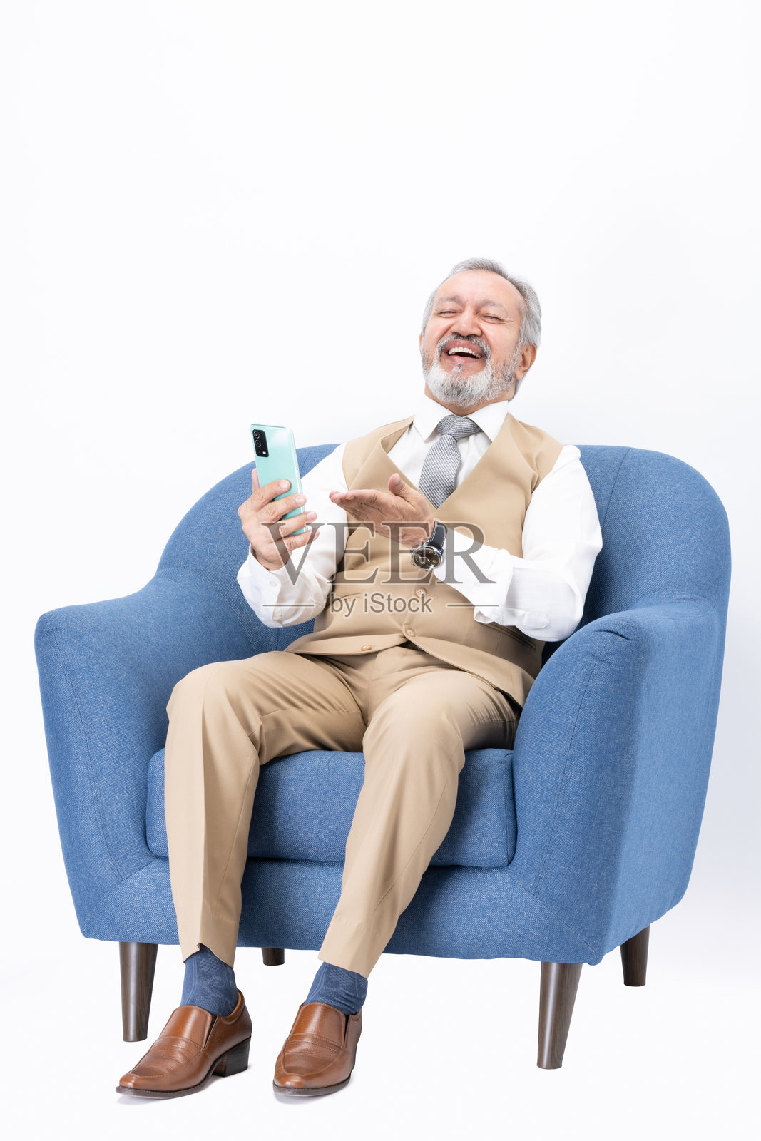 坐在沙发上使用手机的老年人，背景为白色。照片摄影图片