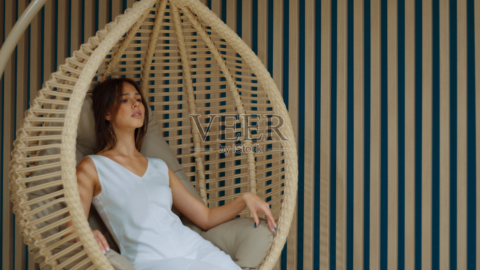 年轻女性在现代房间的吊椅上放松照片摄影图片