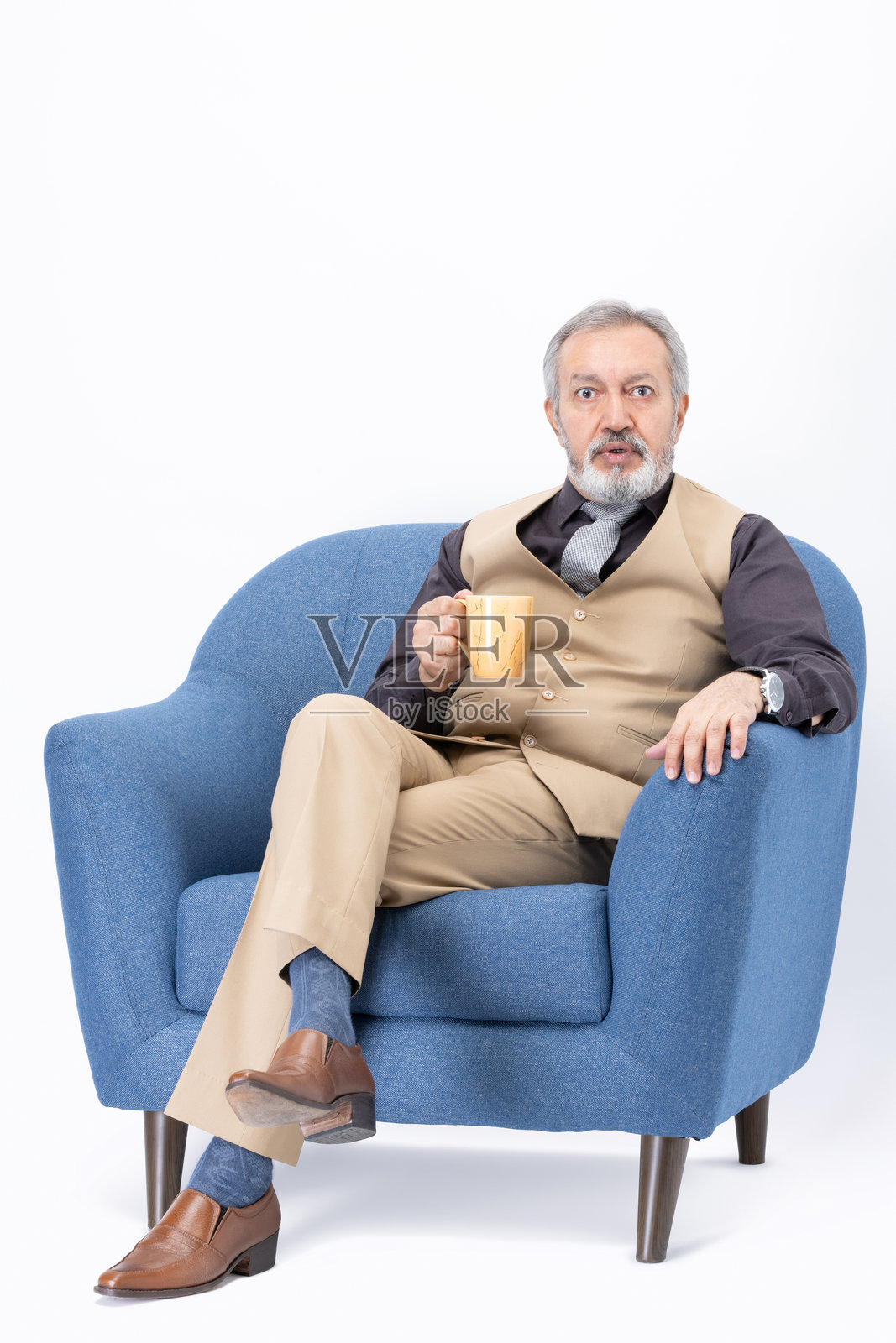 坐在沙发上喝咖啡的老年人，背景为白色。照片摄影图片