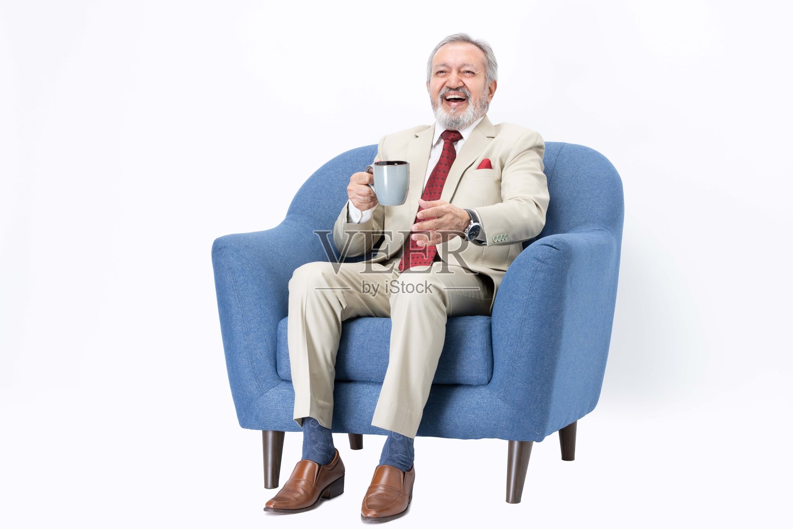 坐在沙发上喝咖啡的资深商人，背景为白色。照片摄影图片