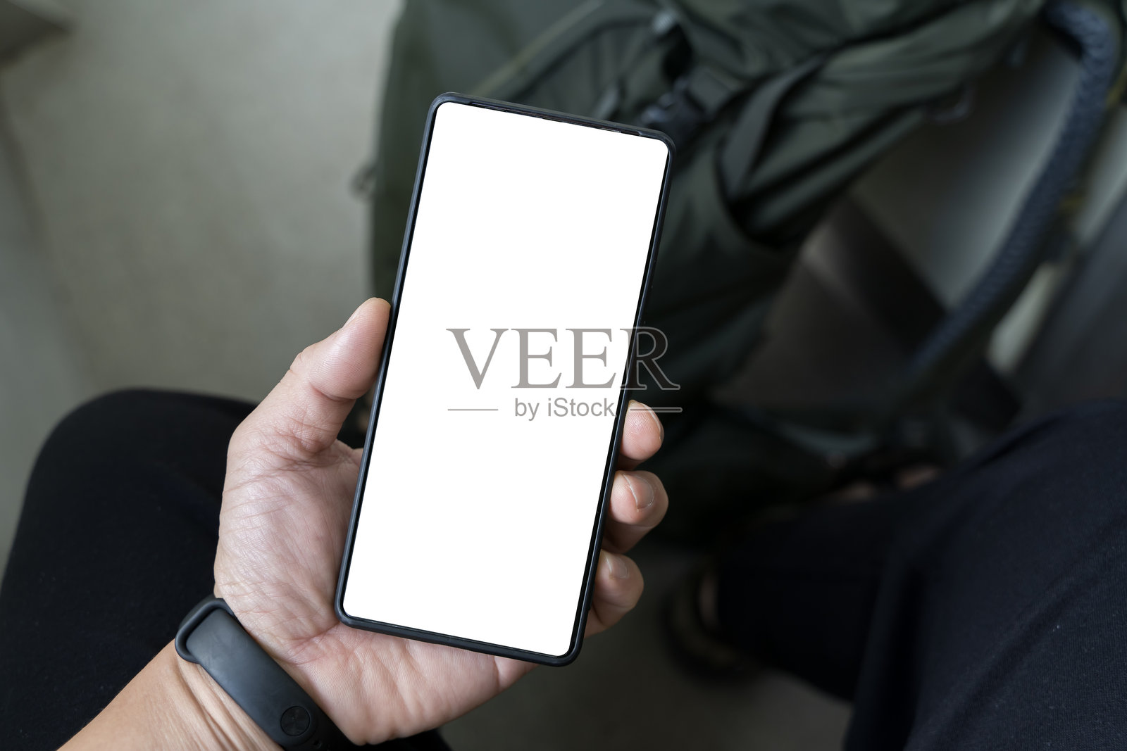 旅客在机场候机厅手持行李，展示手机上的空白空间。照片摄影图片