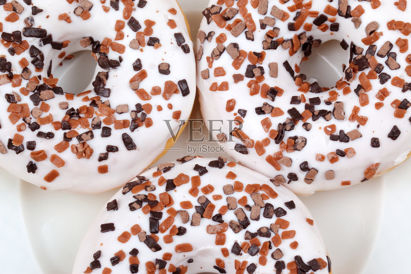 尽情享受这些美味可口、令人愉悦的糖霜甜甜圈，上面撒满了五彩缤纷的糖屑。照片摄影图片