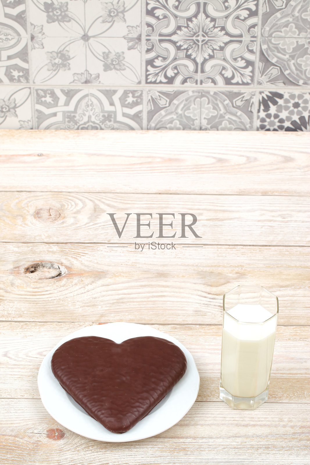享受一块心形巧克力蛋糕，搭配一杯牛奶，摆放在质朴的木桌上。照片摄影图片