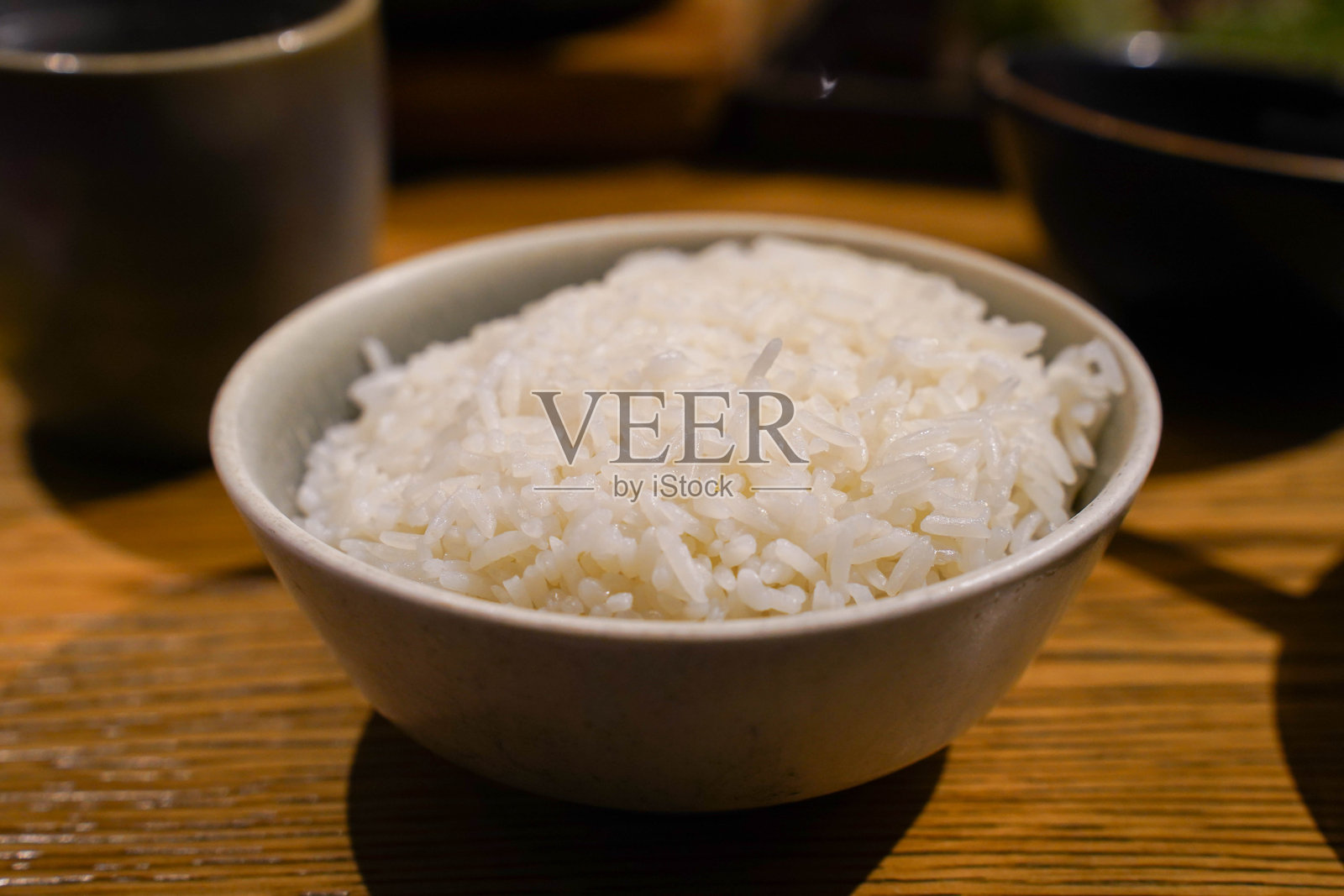餐厅木桌上盛着煮熟米饭的碗照片摄影图片
