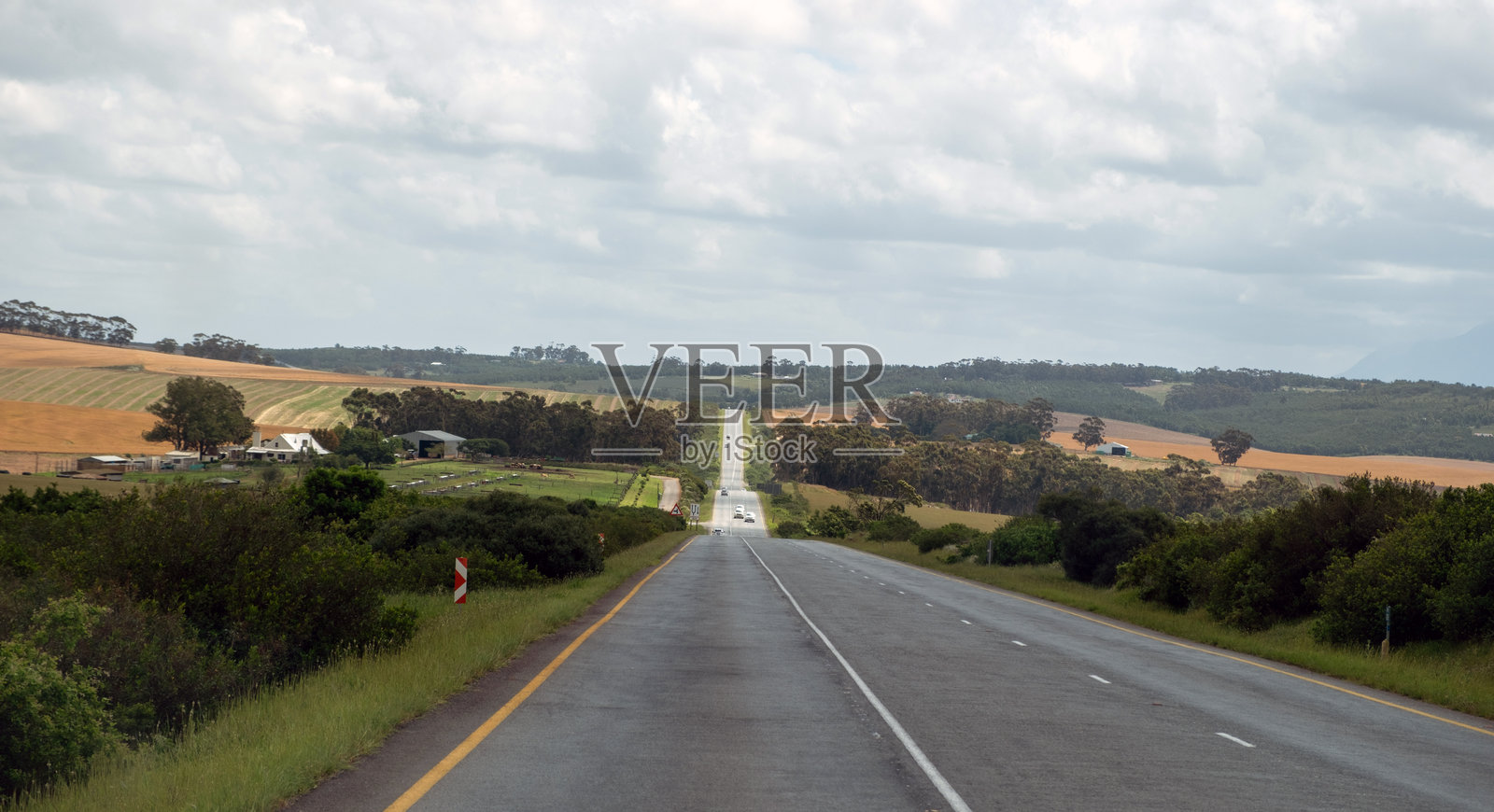 南非乡村的高速公路。沥青路面笔直延伸，周围是田野和农田，天空多云，呈现蓝色。照片摄影图片