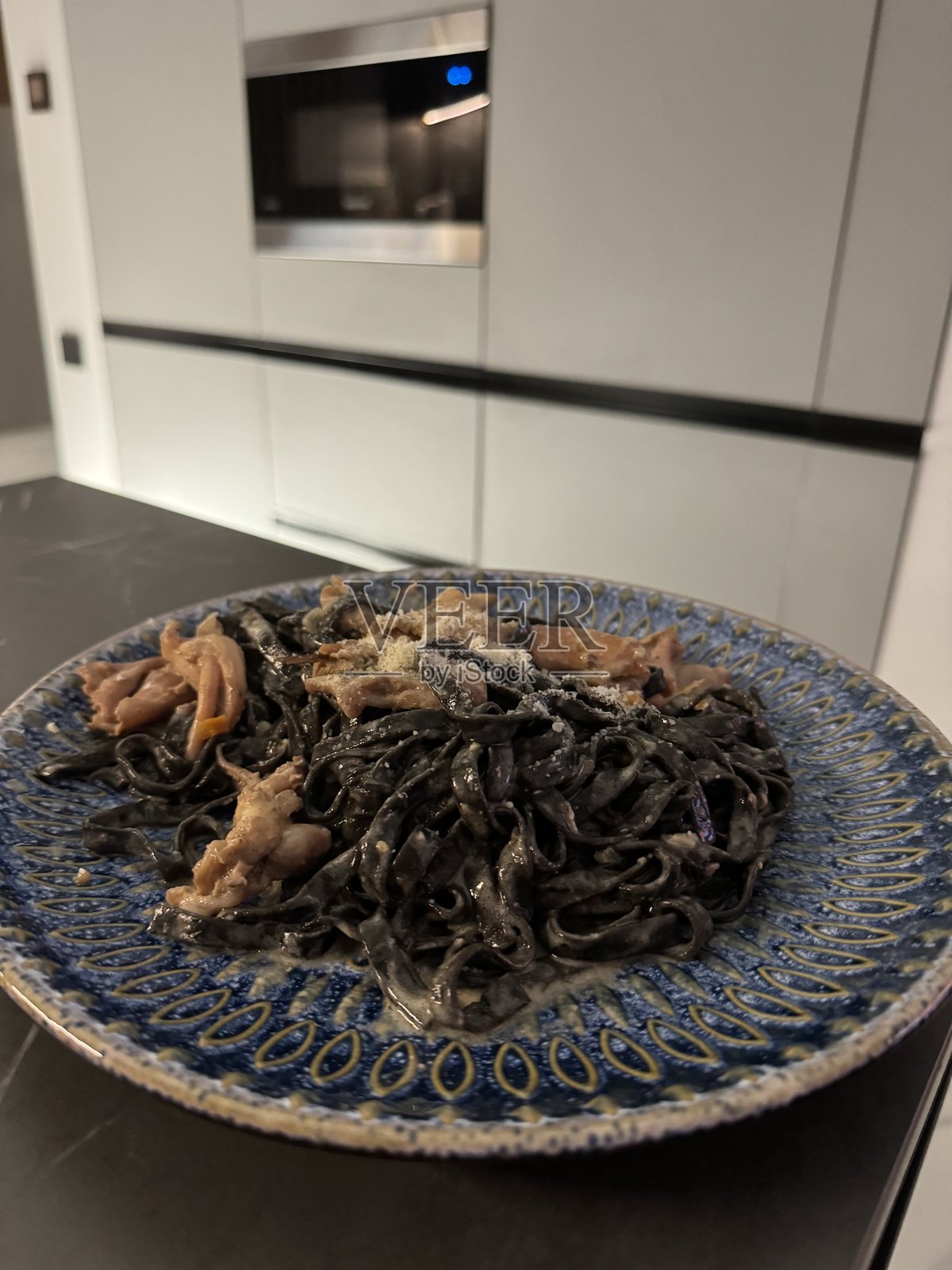 现代厨房环境中的海鲜墨鱼汁意大利面盘照片摄影图片