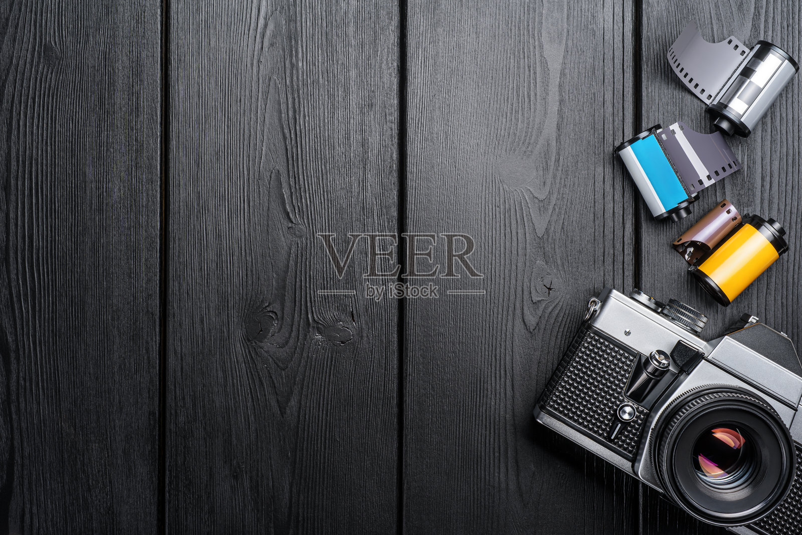 复古金属相机与色彩缤纷的胶卷放在古朴的木桌上。照片摄影图片