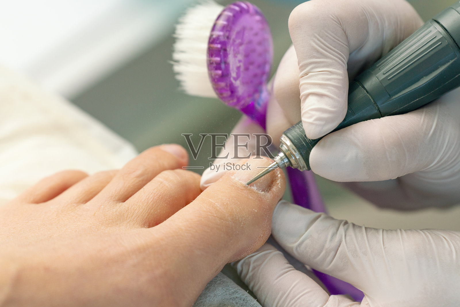 专业的硬件足疗师，足病医生使用指甲磨机清洁指甲照片摄影图片