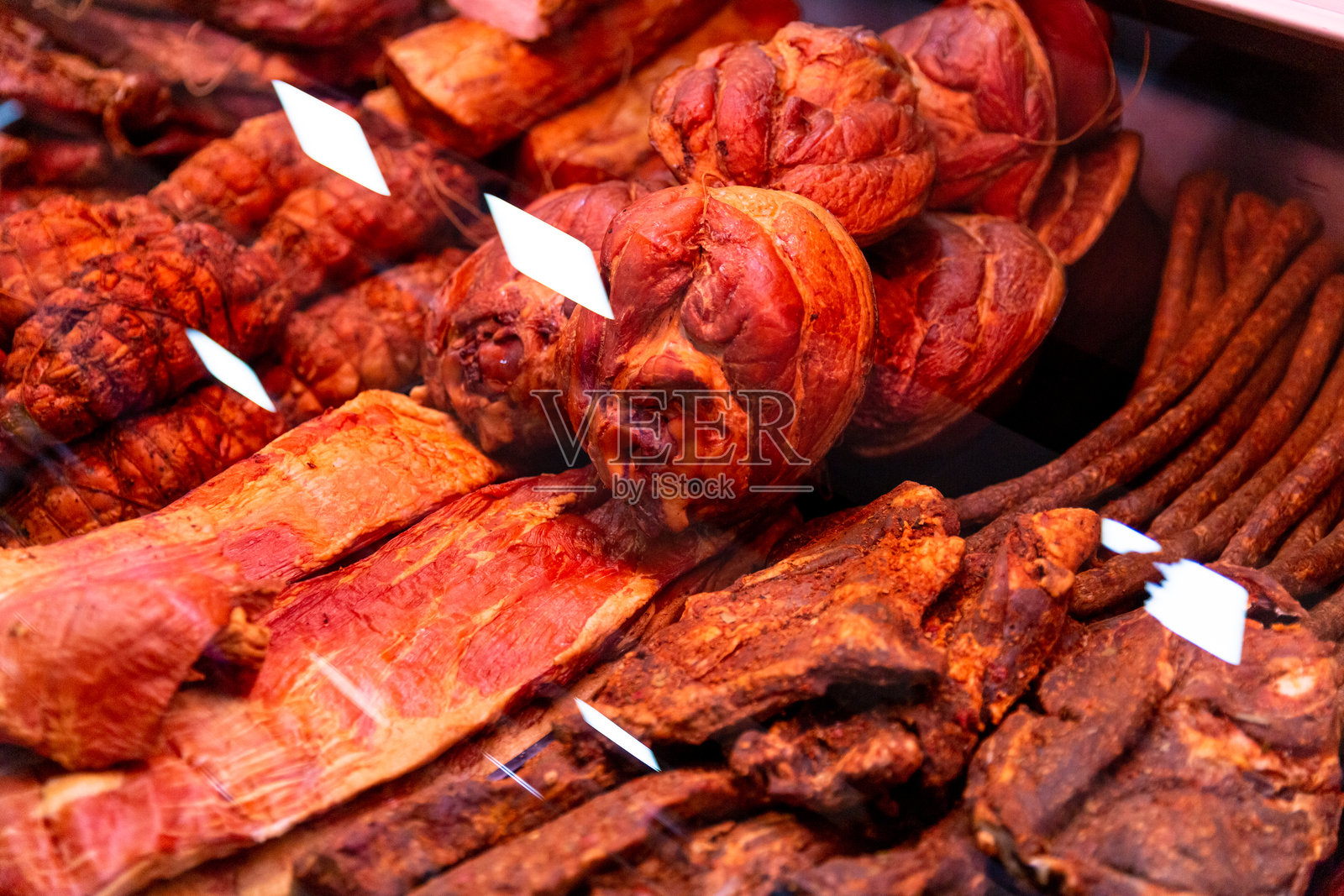 新鲜熏制的香肠和火腿在肉铺的柜台上。照片摄影图片