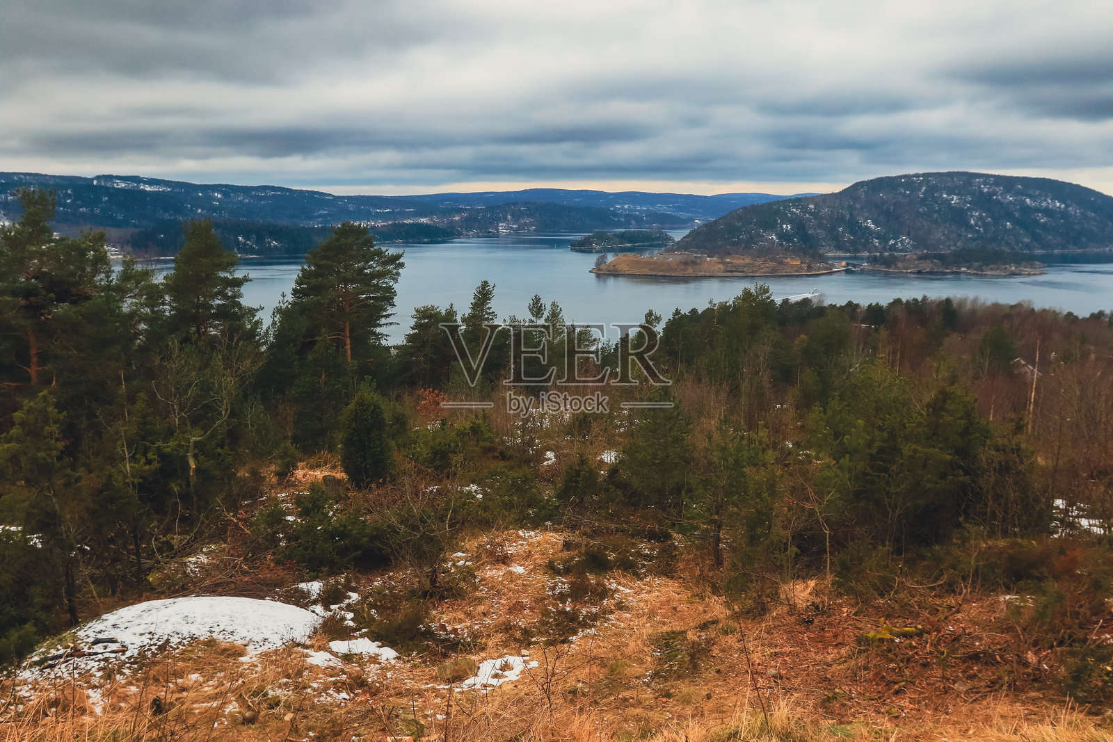 挪威宁静的峡湾和郁郁葱葱的森林在阴郁天空下的惊艳冬季景色照片摄影图片