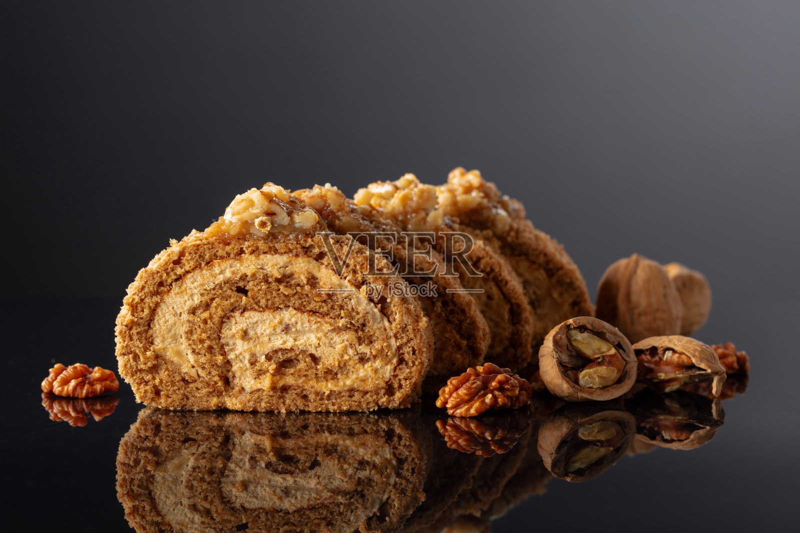 黑色反光背景上的核桃甜点。照片摄影图片