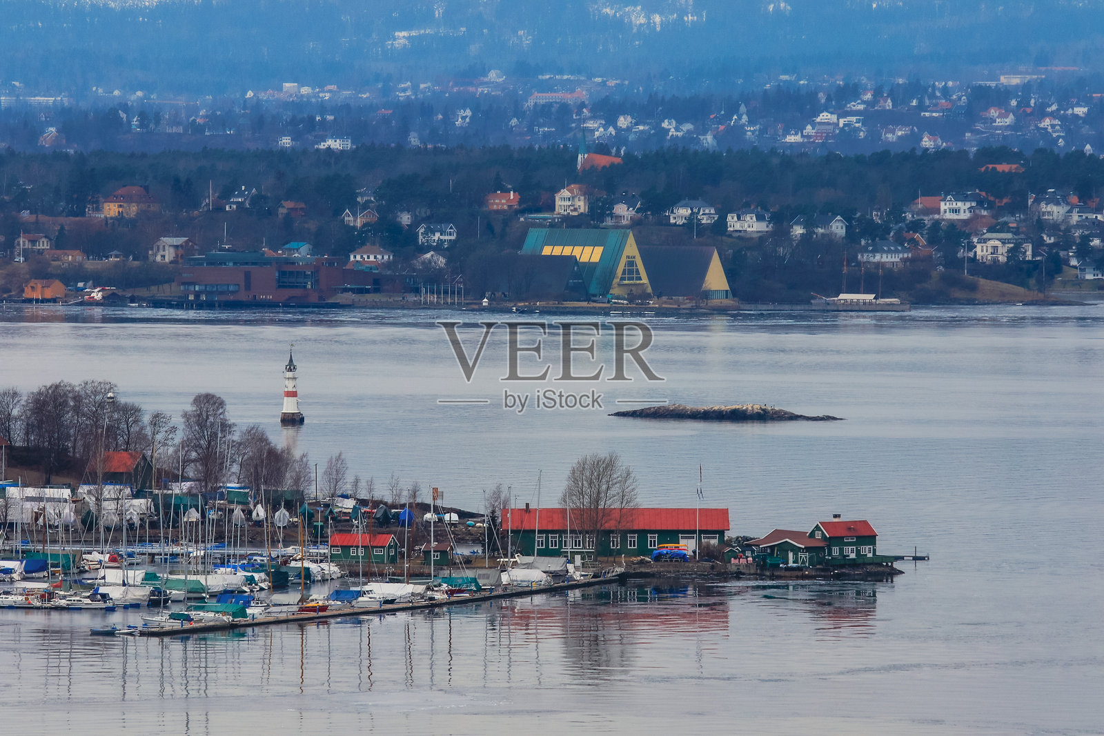 挪威宁静的水面在黎明时分映照出如画的港口景色，岸边停泊着安静的船只。照片摄影图片