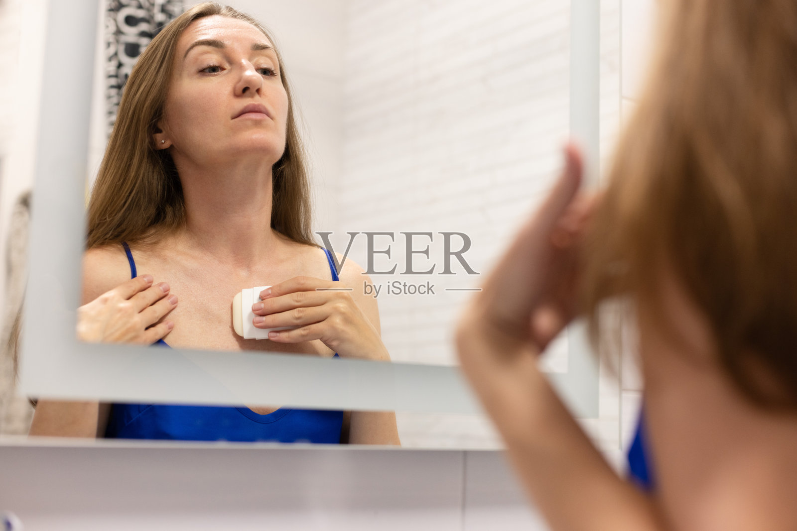 女士用面霜棒来抚平领口的皱纹，或者像防晒霜棒一样。照片摄影图片