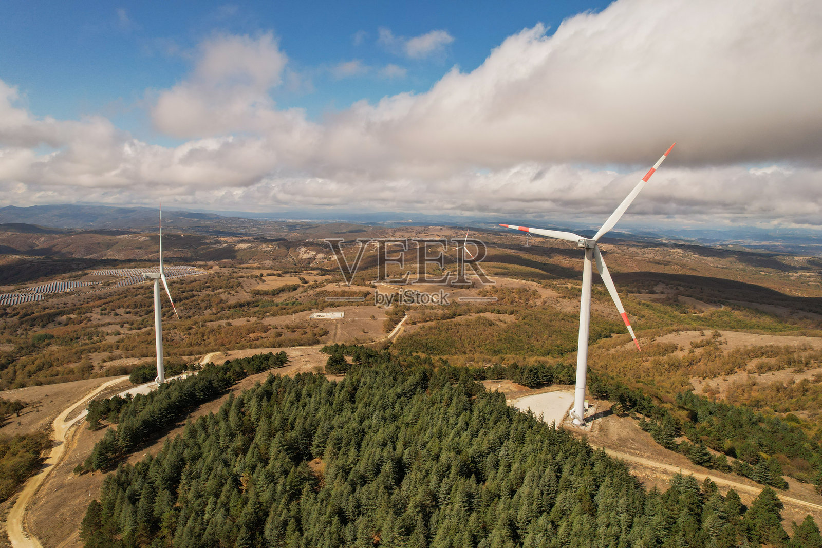 森林地区的风力涡轮机在多云天气中。可再生能源来源照片摄影图片