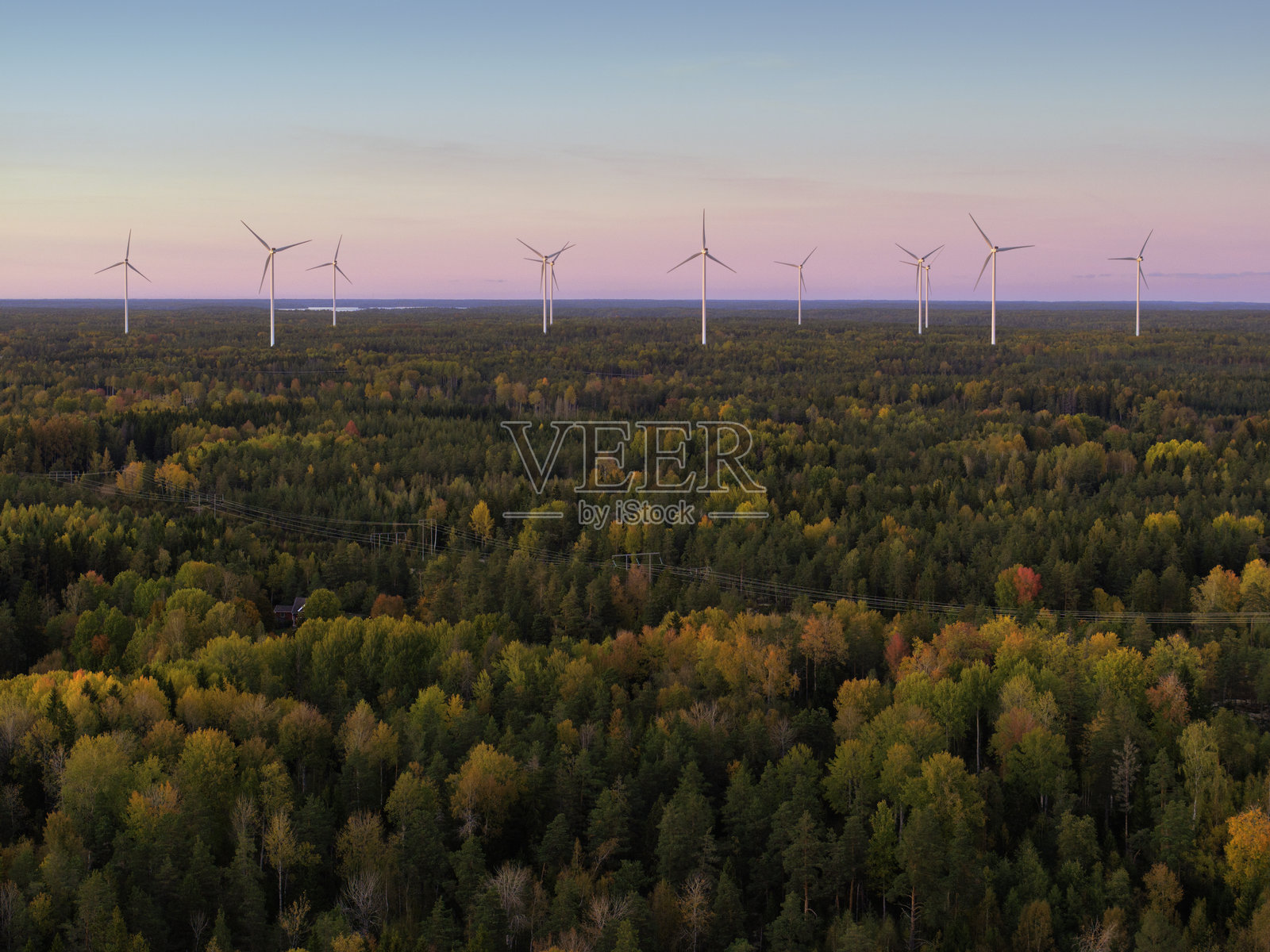 秋季森林的鸟瞰图，背景中有风力发电机照片摄影图片